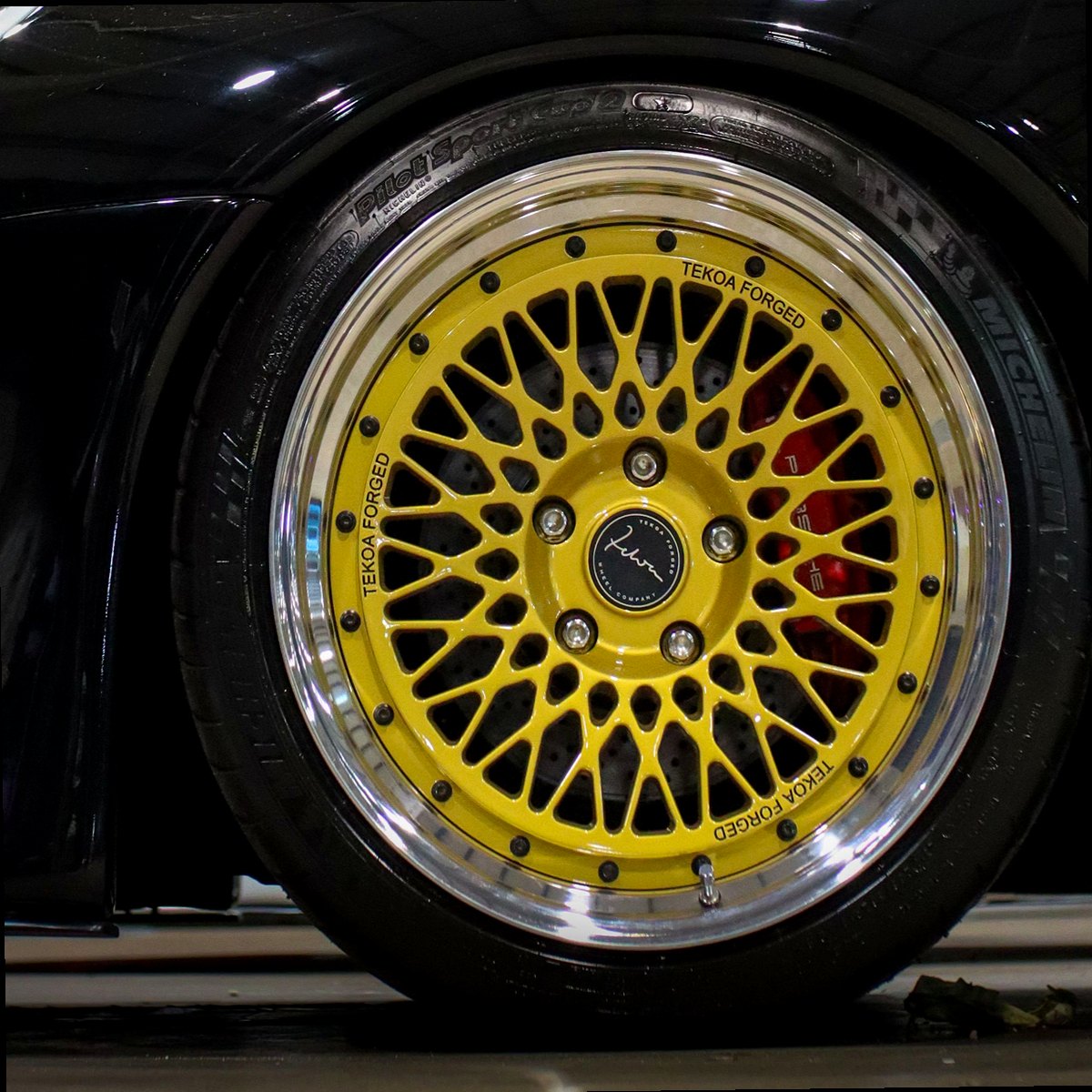Yellow-gold mesh alloy with a polished lip on a black car